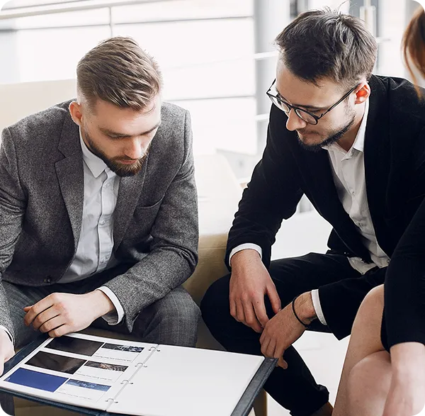 Dos profesionales revisando un libro con información corporativa, imagen utilizada para ilustrar el servicio de reingeniería corporativa de RS Consultoría.